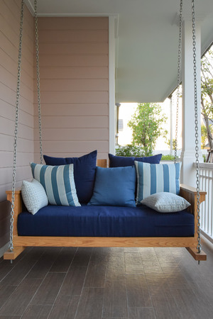 vintage wooden swing with blue pillows at homeの写真素材
