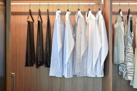 row of white shirts hanging in wooden wardrobeの写真素材