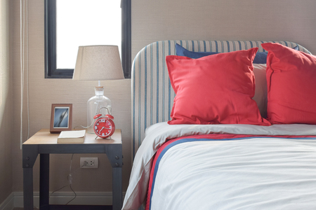 Red and blue pillows on the cozy bed with striped headboardの写真素材