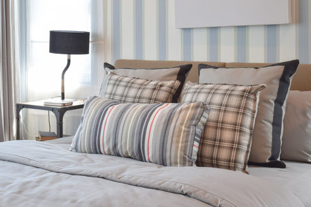 stylish bedroom interior design with striped pillows on bed and decorative table lamp.