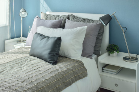 Gray, dark gray and beige pillows on bed with blue wall bedroom
