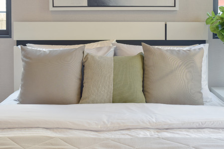 modern bedroom interior with brown and green pillows on white bedの写真素材