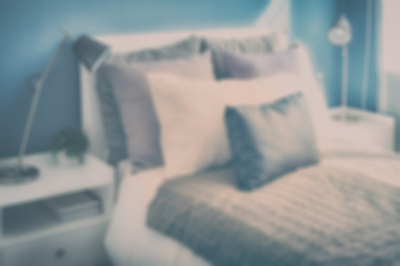 blur image of decorative pillows on bed with blue wall bedroomの写真素材