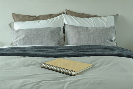 Notebook on bed with gray color scheme beddingの写真素材