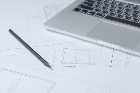 black pencil and computer laptop on architectural drawing paper for constructionの写真素材