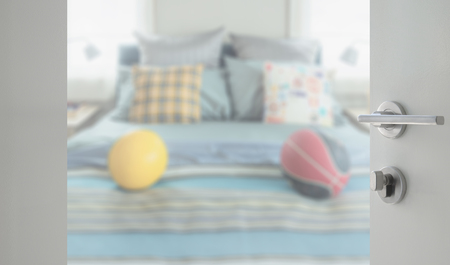 opened white door to bedroom with decorative pillow and football on bedの写真素材