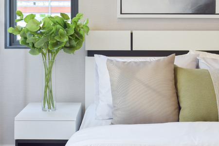 modern bedroom interior with brown and green pillows on white bedの写真素材