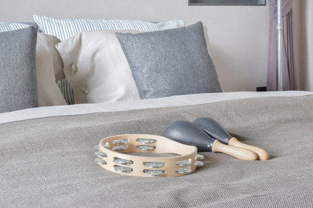 Tambourine and maracas setting on bed with gray color scheme bedding in the bedroom