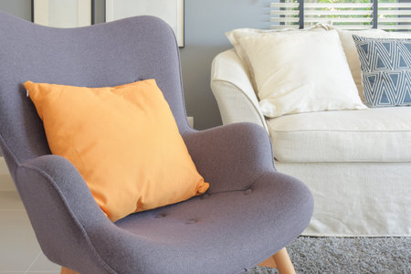 Orange pillow on retro style armchair in living room