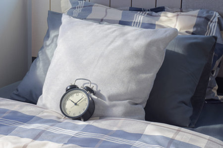 Retro style clock on checked blanket with white pillow in background