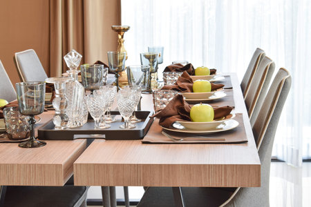 dining wooden table and comfortable chairs in modern home with elegant table setting