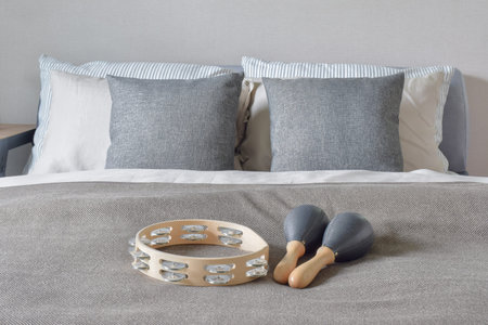 Tambourine and maracas setting on bed with gray color scheme bedding in the bedroom