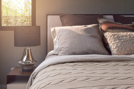 Elegance style pillows setting on classic style bedding and reading lamp on bedside table-sunlight...