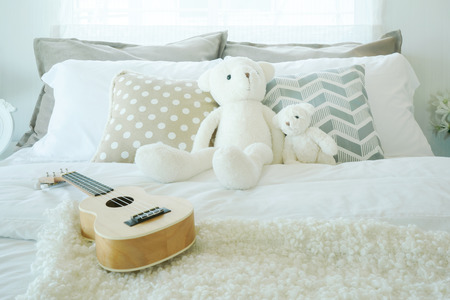 Ukulele and teddy bear on bed in kid bedroom interiorの写真素材