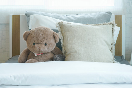 Brown bear and pillows on bed in child's bedroomの写真素材