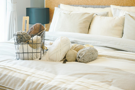 Knitting wools on bed in light brown bedroom interior decorationの写真素材