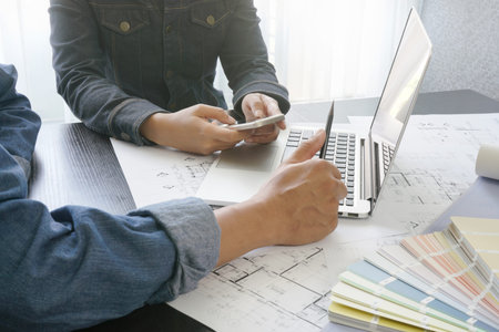 architects and engineer discussing on working table with blueprint and materials sample - business...