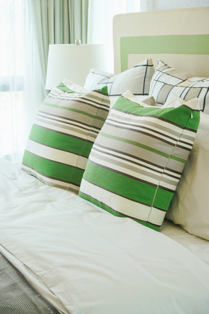 Green stripped pillows setting on bed in modern style bedroomの写真素材