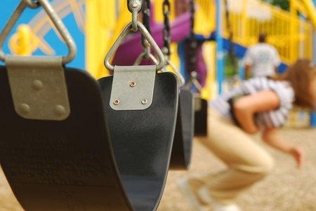 a close up of an empty swing at the playground, focus on swing, shallow depth of field.の写真素材