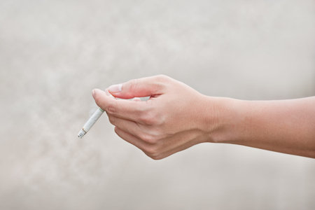 man hand holding a cigarette with smokeの写真素材