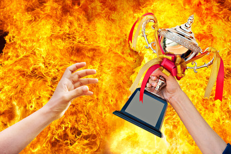 cup with ribbon in hand on fire background