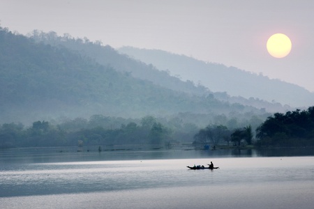 Silhouette of a fisherman in a boat on a lake in the morning の写真素材