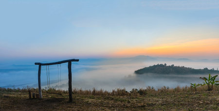 Silhouette the sunrise with the wooden swing, the fog, the beautiful sky and cloud at Phu Lam Duan Mountain, Pak Chom District, Loei Province, Thailand.の写真素材