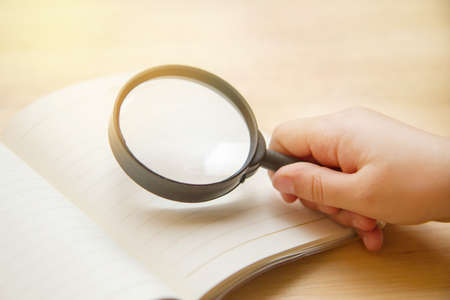kid hand holding magnifier for reading bookの写真素材