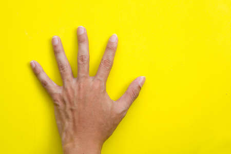 Back left hand on yellow backgroundの写真素材