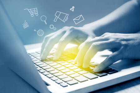 Hand typing on laptop with digital marketing iconの写真素材
