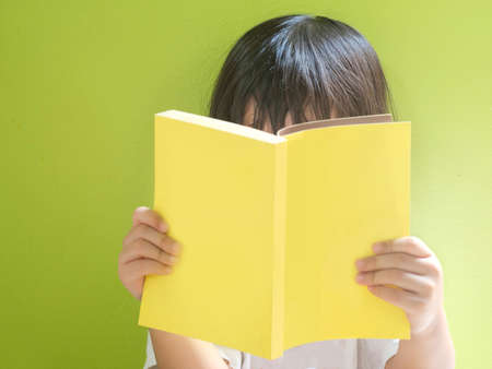 little child reading yellow cover bookの写真素材