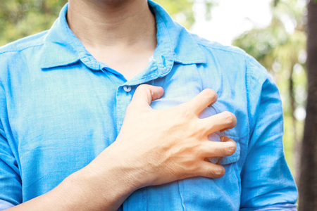 Severe heartache, man suffering from chest pain, having heart attack or painful cramps, pressing on chest with painful expression.の写真素材