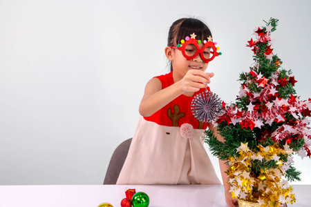Little asian girl decorating christmas tree on white background.の写真素材