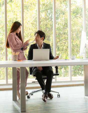 Asian men and women is a new employee in the office are consulting and recommending work with each otherの写真素材