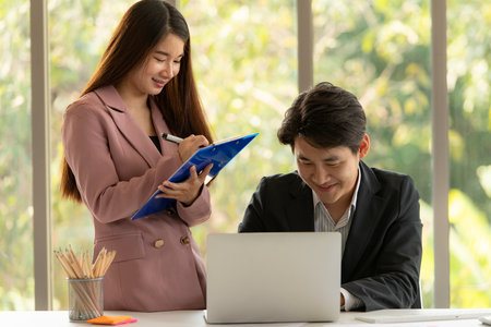 Asian men and women is a new employee in the office are consulting and recommending work with each otherの写真素材