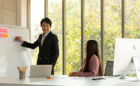 Asian men and women is a new employee in the office are consulting and recommending work with each otherの写真素材