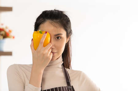 Young woman cooking a hamburger in kitchen with a smile and deliciousの写真素材