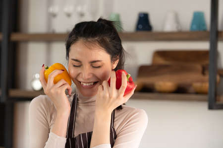 Young woman cooking a hamburger in kitchen with a smile and deliciousの写真素材