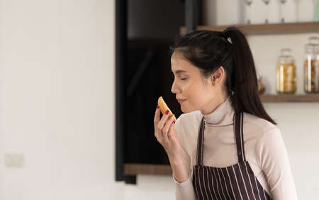 Young woman cooking a hamburger in kitchen with a smile and deliciousの写真素材