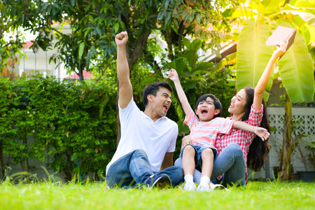 A happy young family spends time playing together in the garden at the front of house the vacation.の写真素材