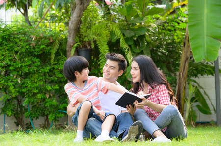 A happy young family spends time playing together in the garden at the front of house the vacation.の写真素材