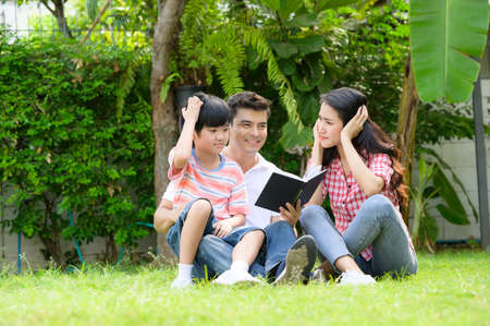 A happy young family spends time playing together in the garden at the front of house the vacation.の写真素材