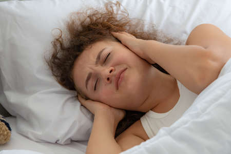 Woman relaxing in the white bedroom of the apartment with various emotionsの写真素材