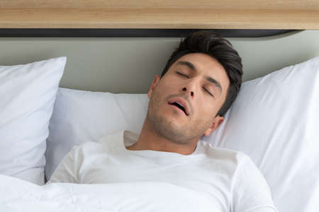 Man was sleep and snore in the white bedroom of the apartmentの写真素材