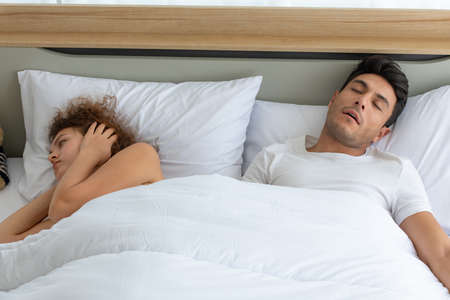 Happy couples relaxing in the white bedroom of the apartment with various emotions in the morningの写真素材