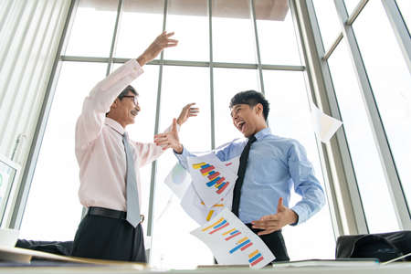 Senior businessman With a new generation of business people celebrating success together happily.の写真素材