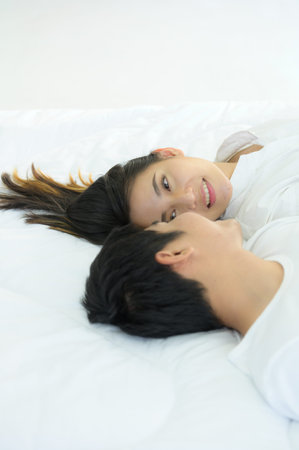 Couples are happy to relax in the white bedroom and share love with each other.の写真素材