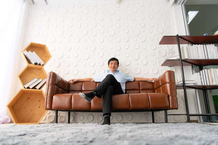 Senior businessmen relax from work in a private office to relax from business stress. By sitting watching a movie from a tablet play games on VR or read books.の写真素材