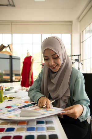 Muslim women run a small business in their own homes. Is the design and tailoring of clothes.の写真素材