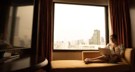 A young businesswoman who travels all over the world to do business. must stay and live in a hotel as a place to relax and sleep as well as used as a workplaceの写真素材